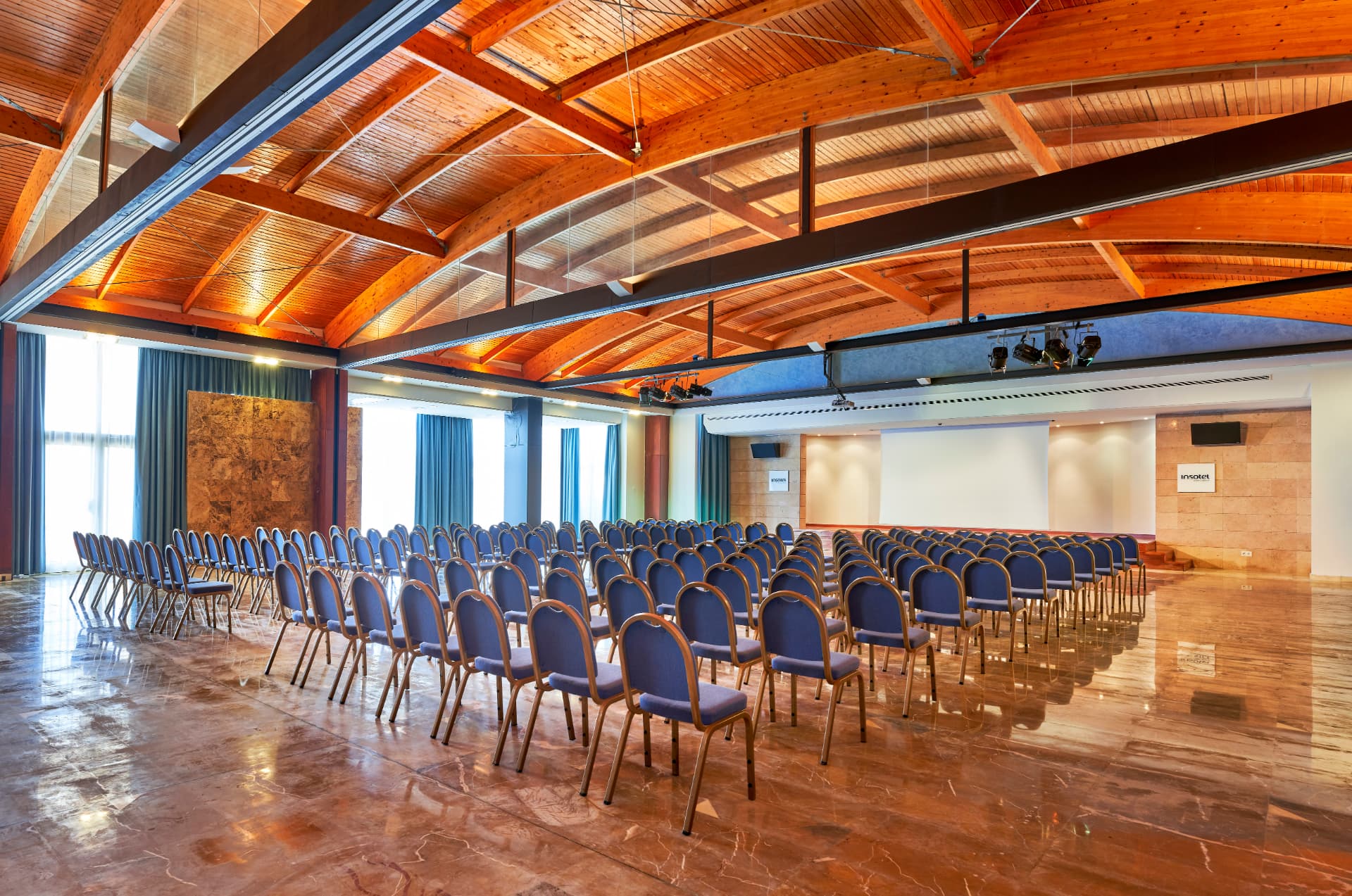 Sala de conferencias con sillas dispuestas en auditorio y pantalla de proyección